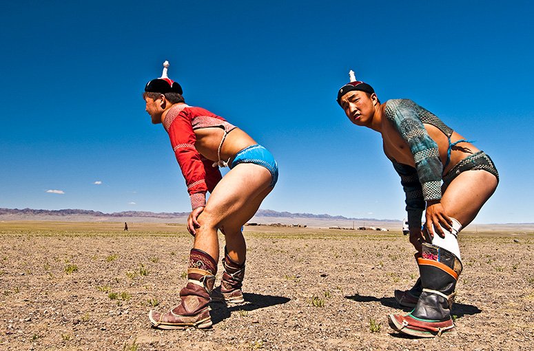 Mongolian wrestling (known as bokh) is one of Mongolia’s most popular sports. During the national Naadam* Festival, held in Ulaanbaatar, 512 wrestlers compete in a single elimination tournament of nine rounds but in rural areas there may be a smaller number of rounds. *Naad means games and Naadam (Erviin Gurvan Naadam) highlights the three manly sports of wrestling, archery and horse racing. Naadam is a favoured public holiday, one of Mongolia’s top sporting events, a celebration of culture and tradition and pride, and a vibrant traditional Mongolian festival. In all wrestling events there are no age, weight or height restrictions. The object of a match is to get an opponent to touch his back, knee or elbow to the ground by using a range of techniques (mekh– including throws, lifts and trips) based on the assessment of their opponents strengths and/or weaknesses. It is a game of strategy, weight andstrength. All wrestlers wear a typical outfit as seen in this great photo taken by our guest Egon Filter of the Bayandalai Naadam in the southern Gobi. The shodog are the small, tight fitting shorts – designed to make the wrestler more mobile and to prevent the opponent from taking advantage of long pants to get a better grip. Gutal are the boots and the zodog is the wrestlers top. The overall winner of the national Naadam event become a national hero. Its a sport that all members of the EL team absolutely love – including me! You can explore more of the images that Egon Filter took during his Eternal Landscapes Mongolia experience here.