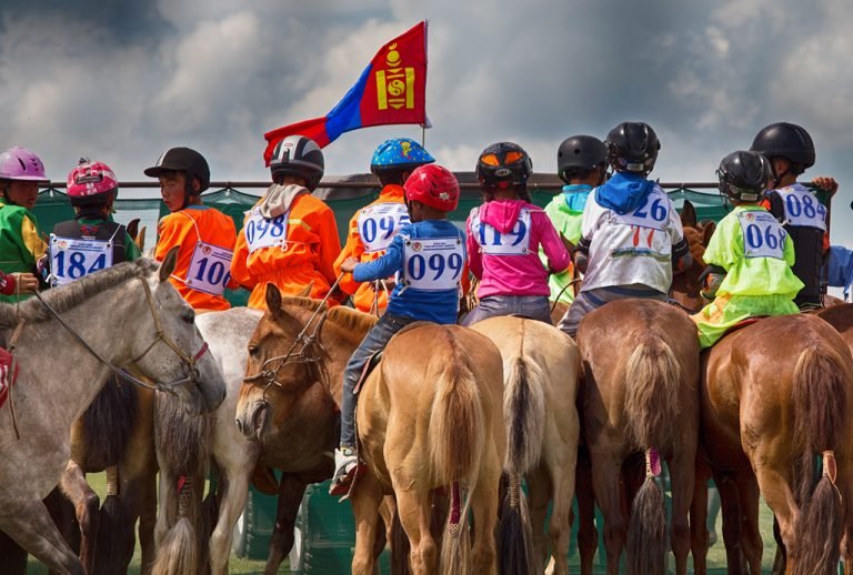 Mongolian children on their horses at the start line of a Naadam Festival horse race