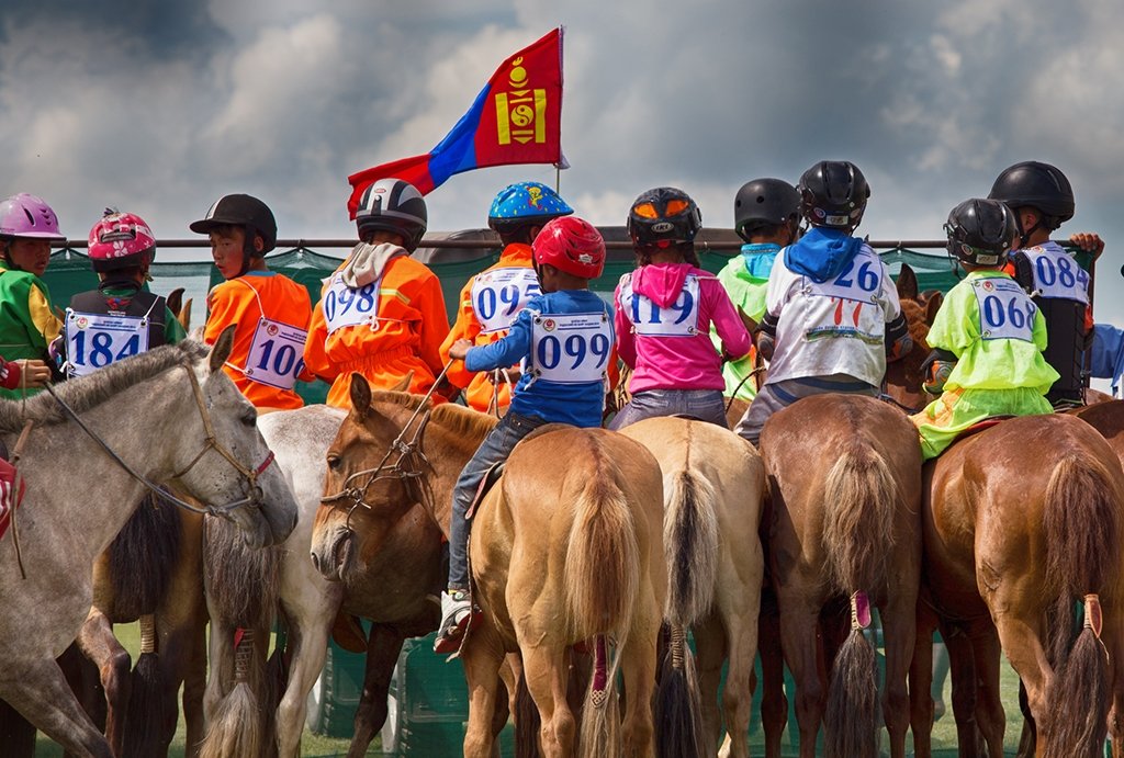 Mongolian children on their horses at the start line of a Naadam Festival horse race. What time of year to visit Mongolia is one of the popular questions about Mongolia