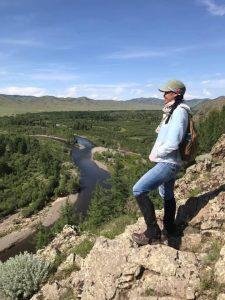 One of our female Mongolian trip assistants is achieving new heights on a trek overlooking a river.