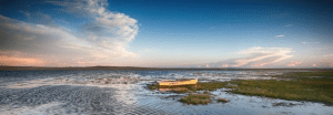 A boat sits in the middle of one of Mongolia's lakes at sunset, offering an intimate experience for small group tours.